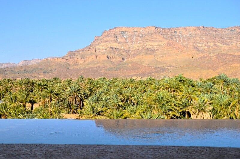 Rutas privadas por Marruecos con una agencia local especializada en un único destino 5 Piscina de un alojamiento con vistas al palmeral y las montañas del Valle del Draa