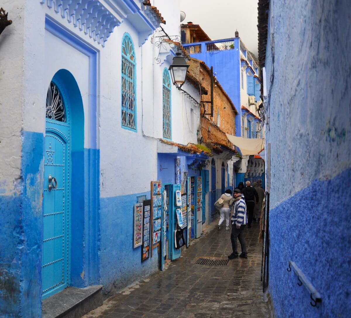 Calle de la medina de Chefchaouen con fachadas azules y puerta turquesa